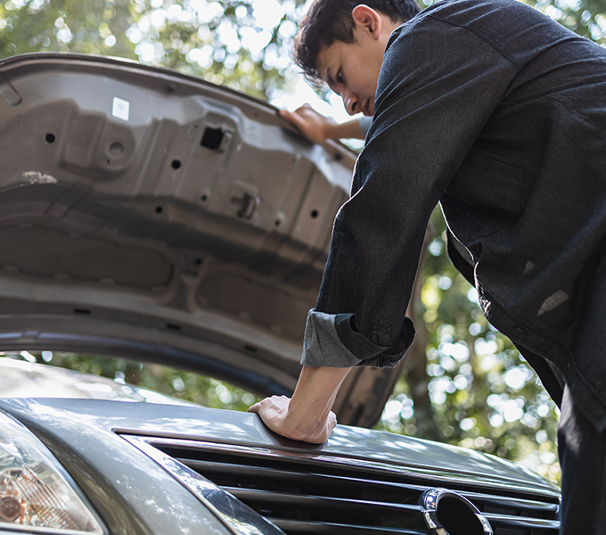 a man looking at the engine of his car while holding up the bonnet